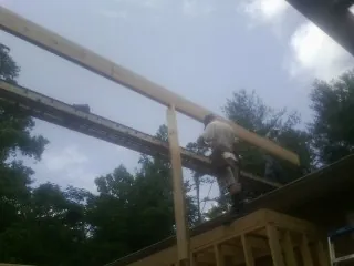 Carpenter setting a ridge beam over a new addition frame — Ice Dam Removal by Roofing Brothers in Grandy
