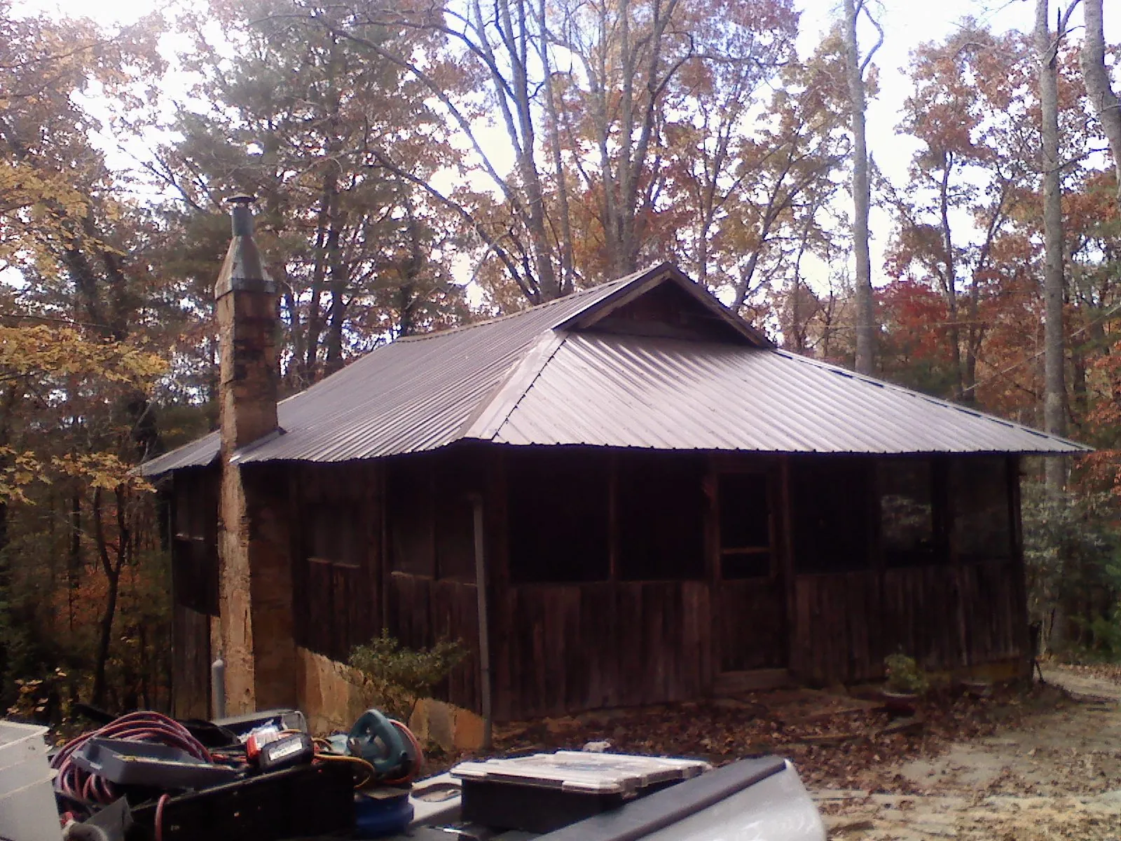 Brown metal hip roof on an old cabin with a stone chimney in Grandy
