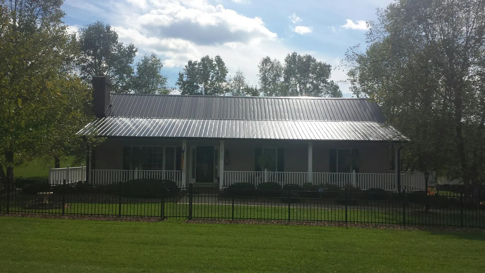 Gray metal roof on a brick ranch with a full width front porch — Gutter Guard Installation work by our crew in Grandy