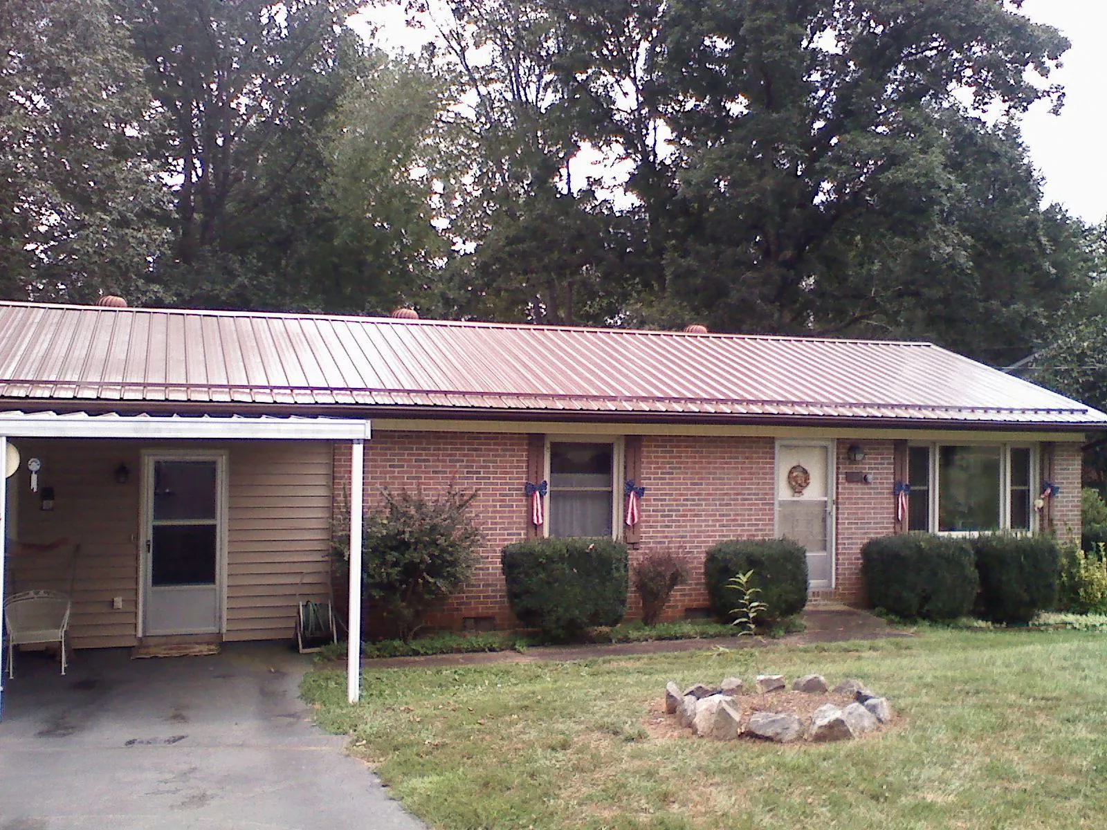 Bronze metal roof and carport on a brick ranch home — Roof Repair work by our crew in Grandy