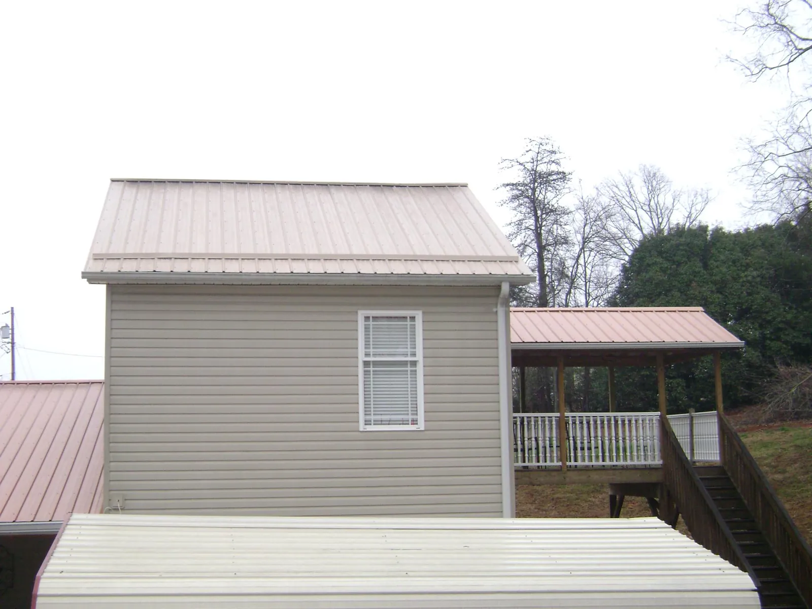 Tan metal roofs on a two story addition and attached porch, from a Roof Replacement job in Grandy