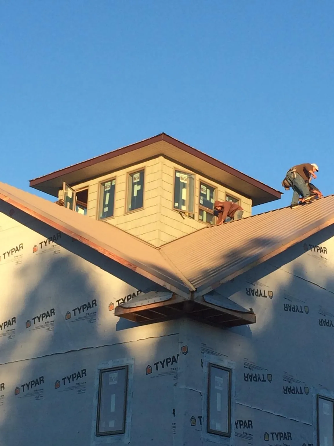 Roofers working around a rooftop cupola on a new metal roof at sunset — Roof Waterproofing in Grandy by Roofing Brothers